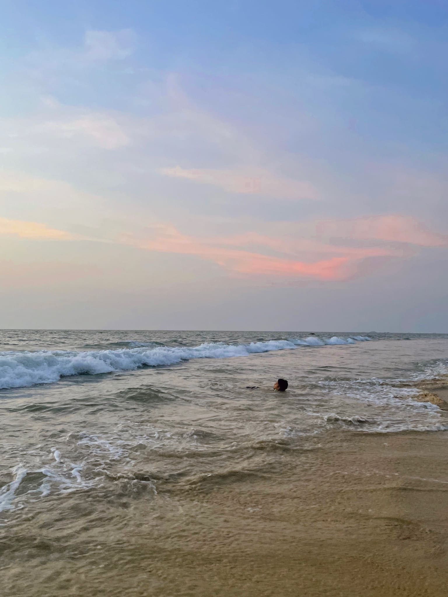The sea at Thottam beach under a pastel sunset sky