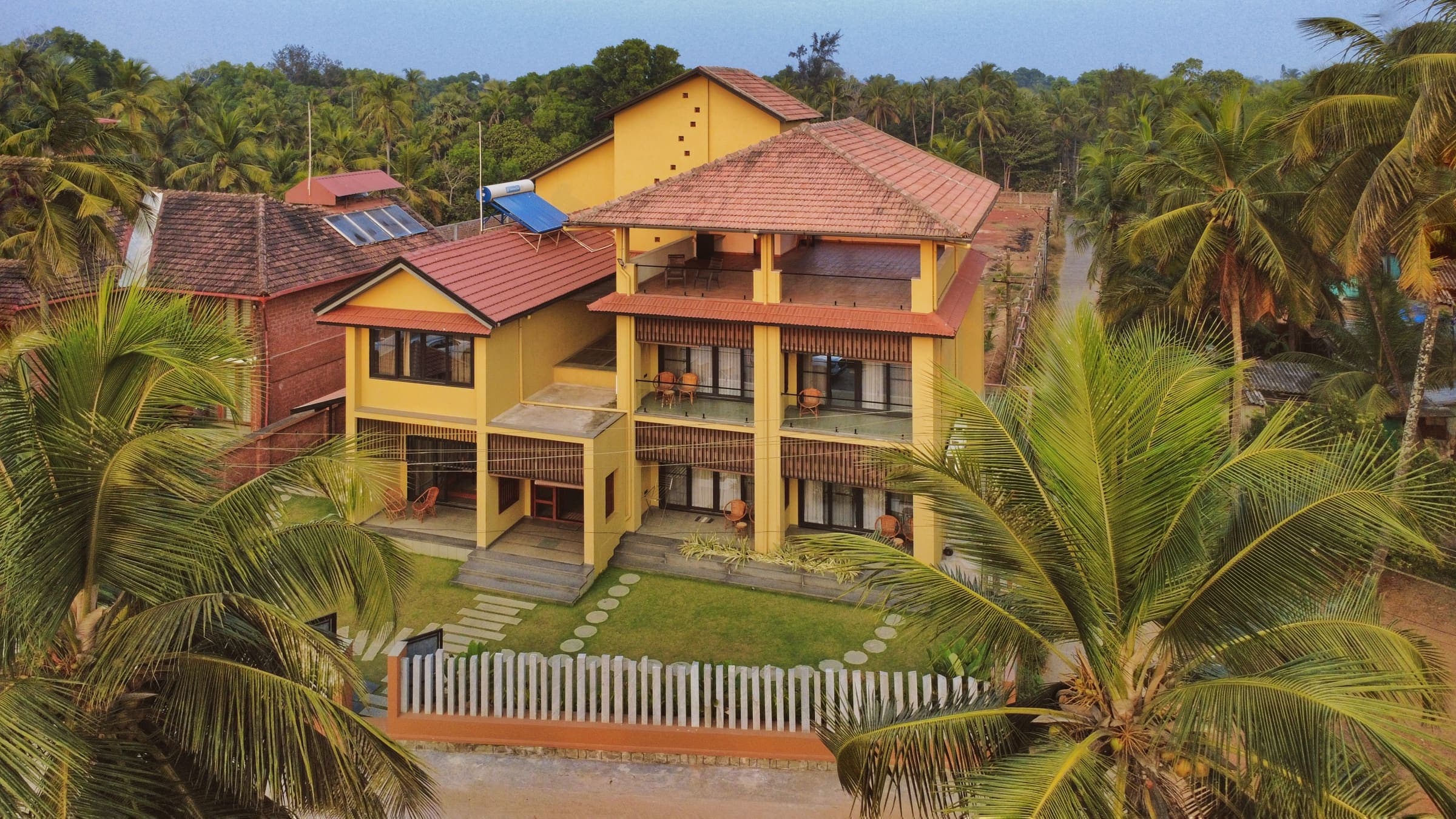 illa By the Sea seen from the beach side, its balconies facing the ocean between coconut palms