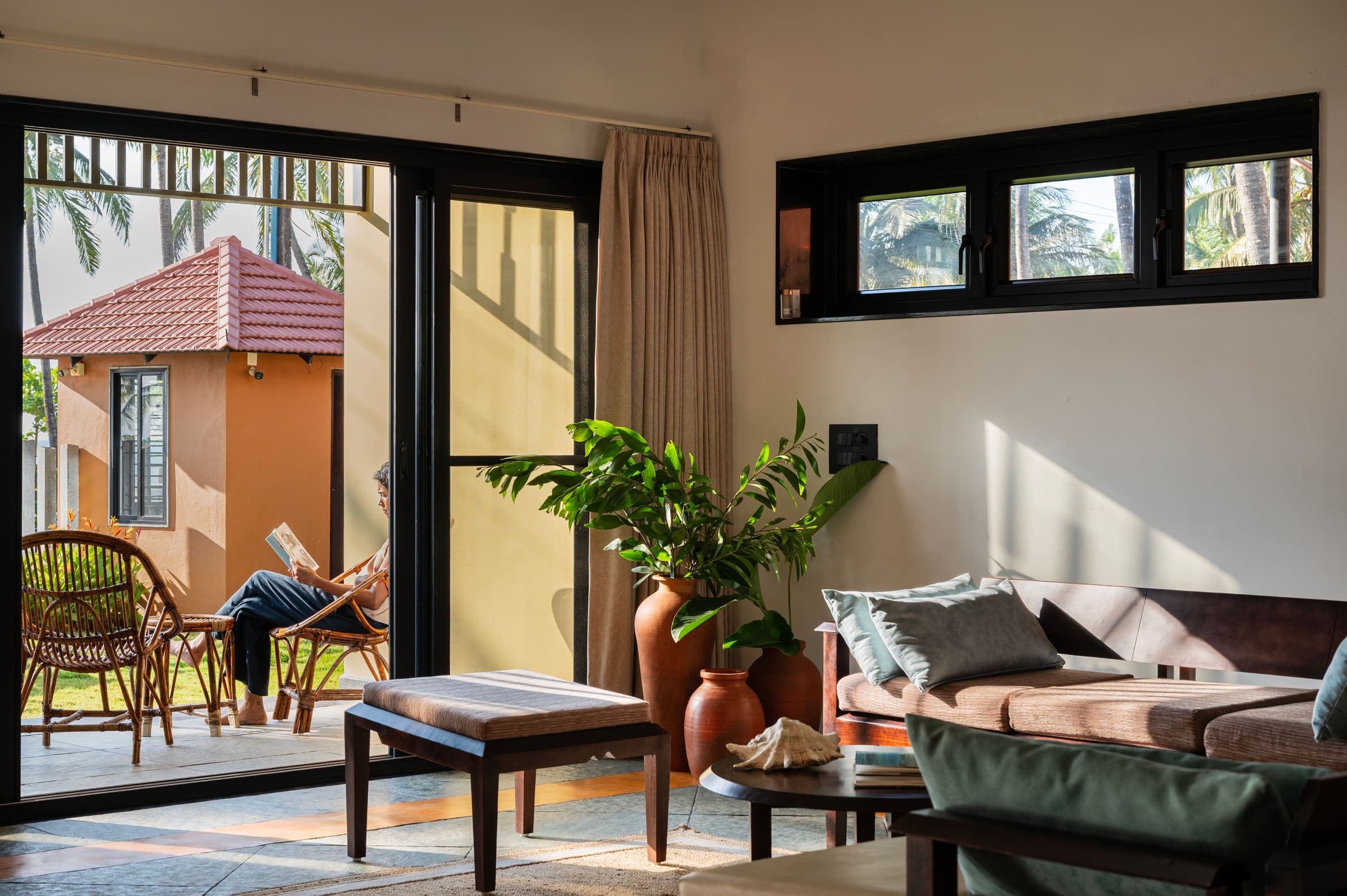 The living room opening onto the verandah, a guest reading in the morning light