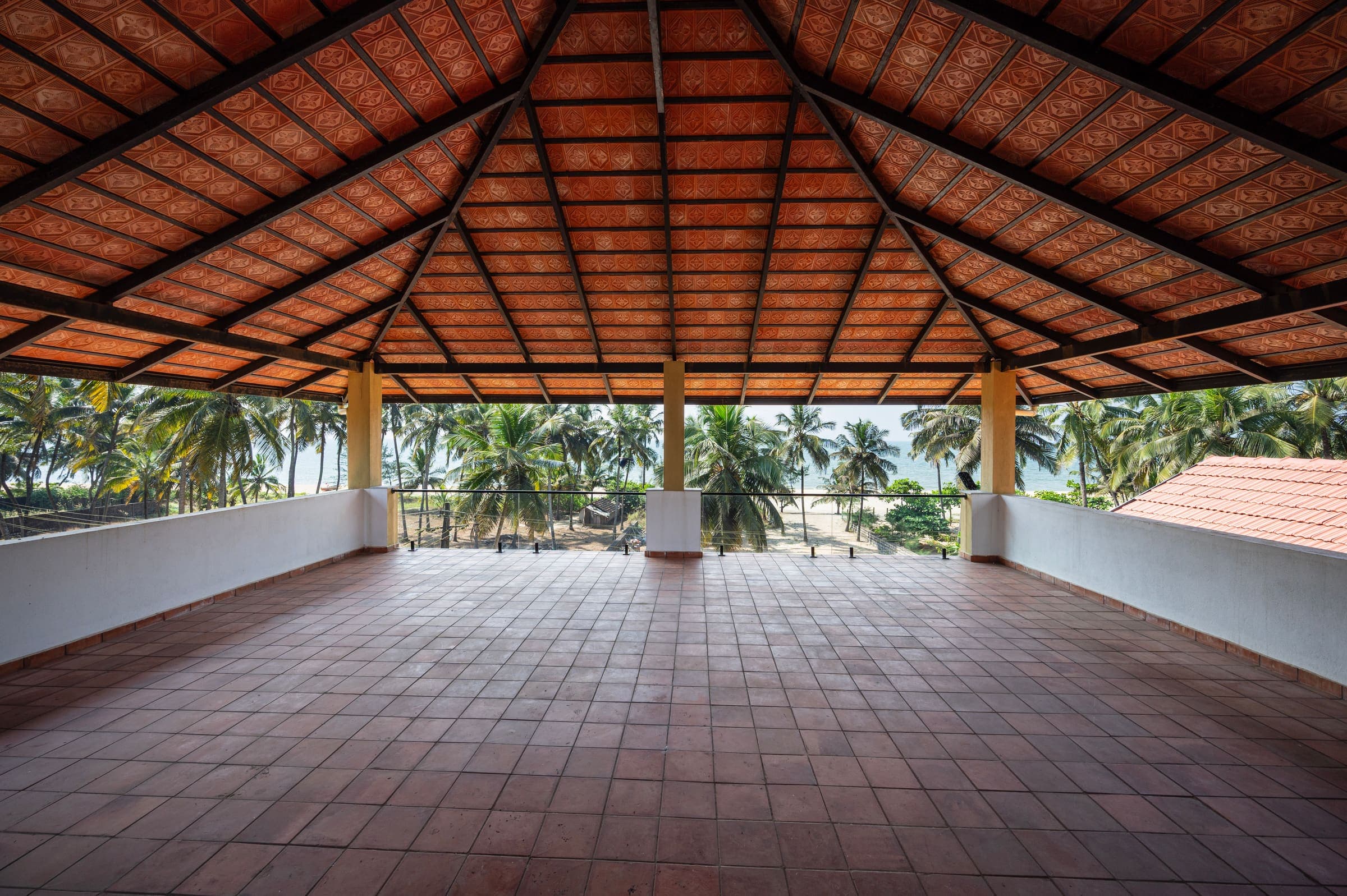 The open rooftop terrace under a tiled roof, looking over coconut palms
