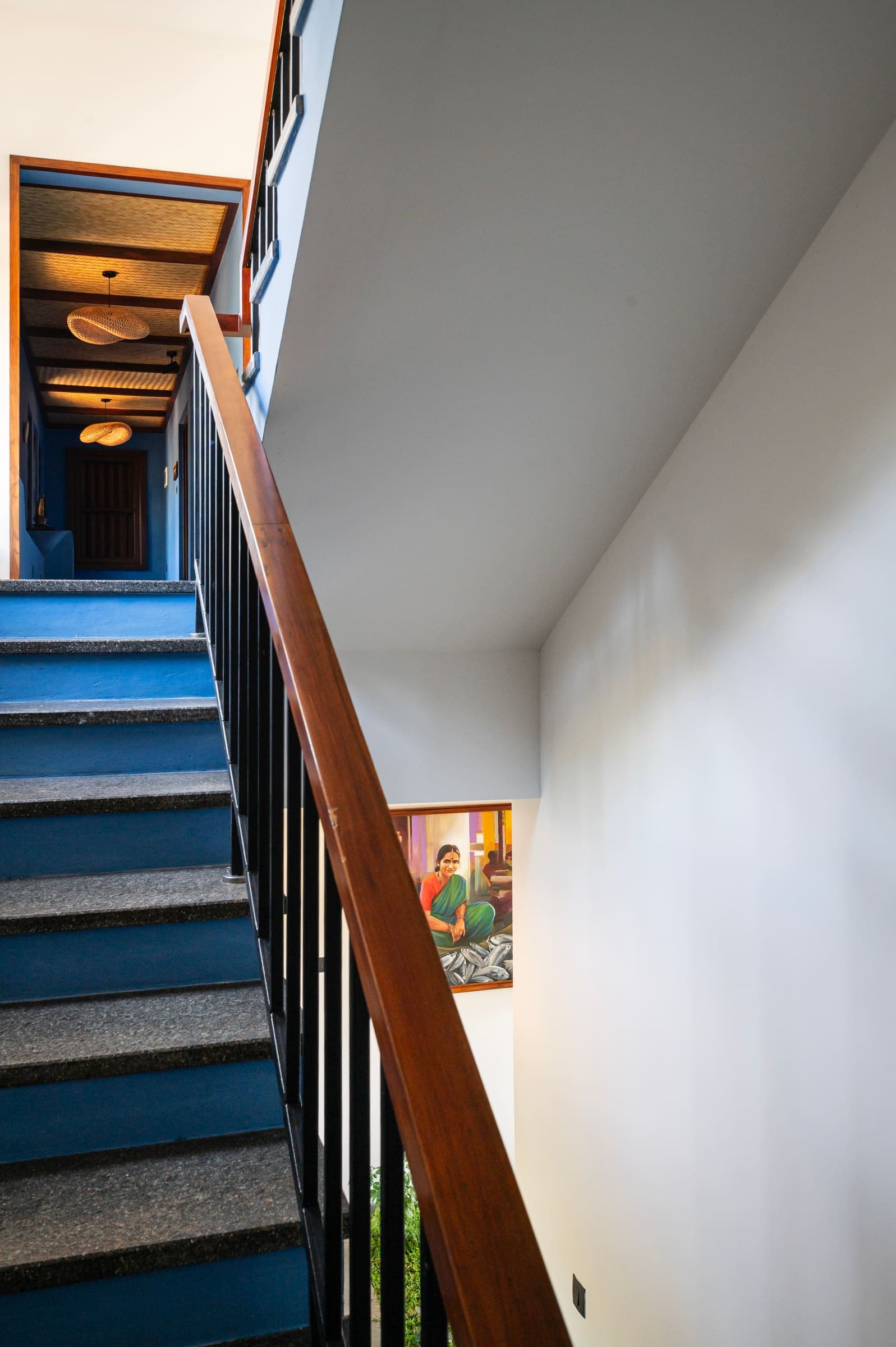 The staircase with a wooden handrail and blue risers