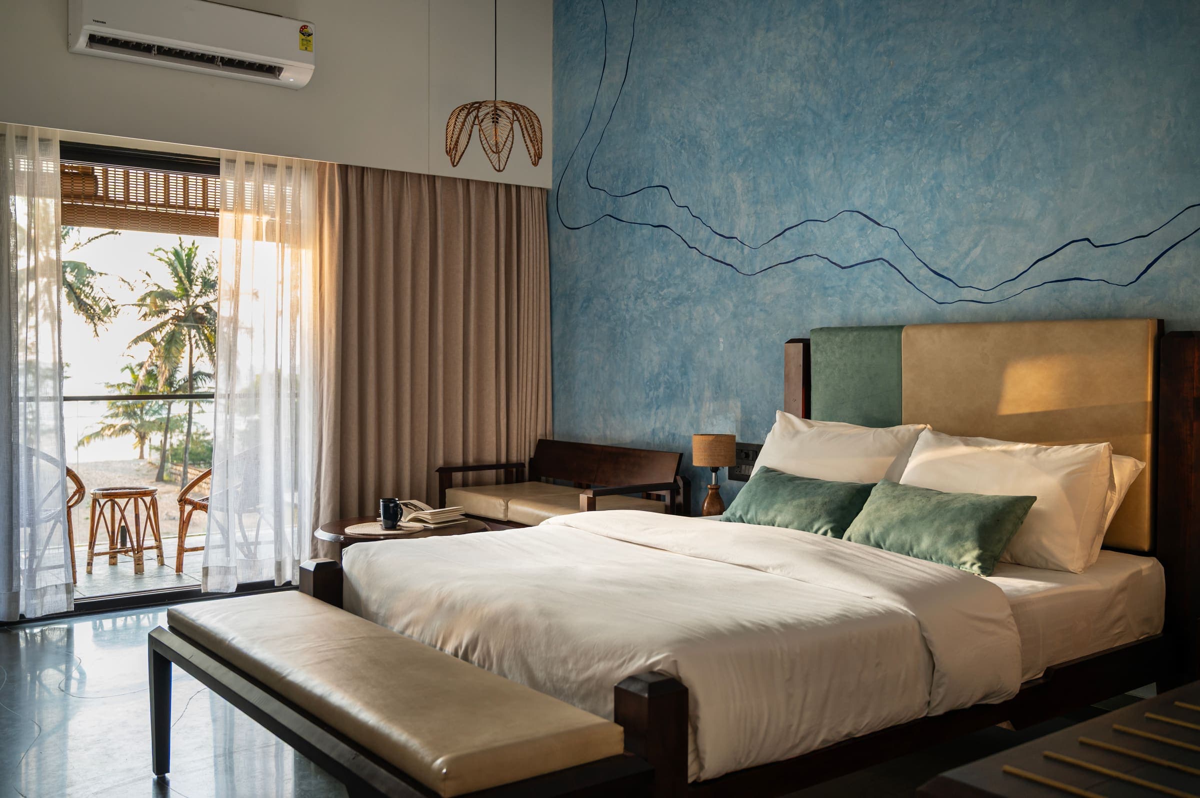 Swarna, in its river-blue palette, with a queen bed and a sea-facing balcony