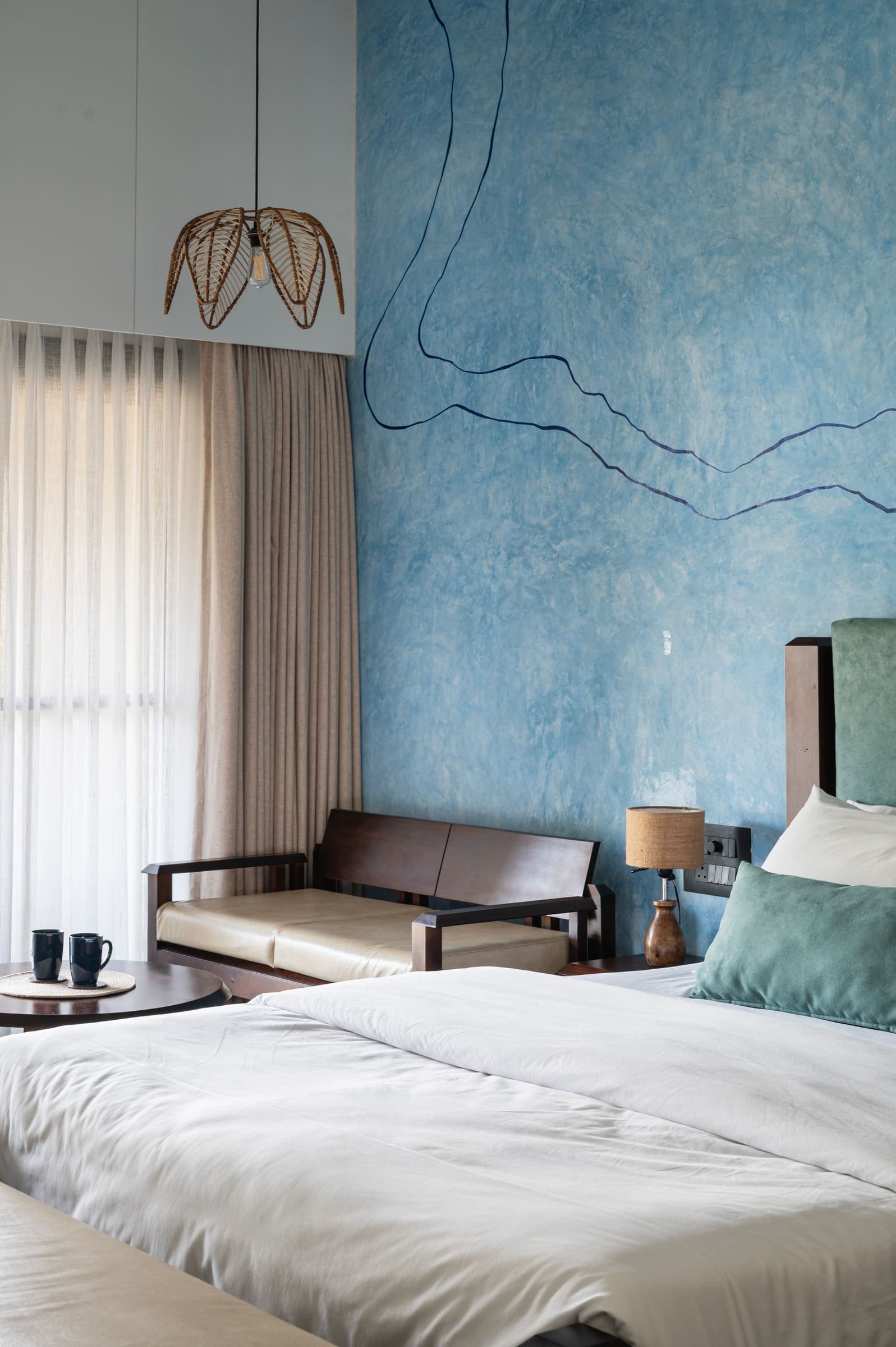 The seating corner of a blue room with a wooden sofa