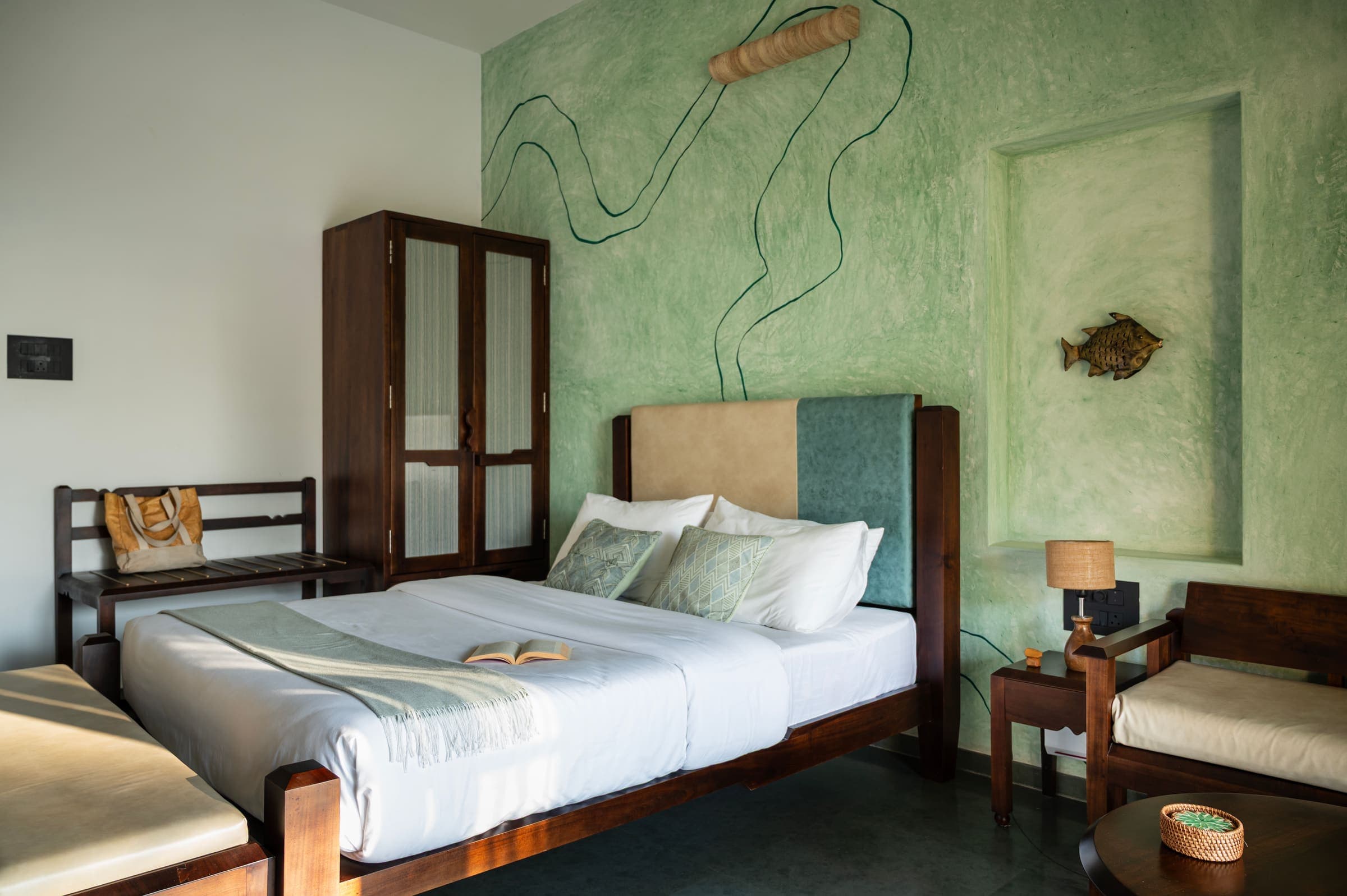 A green-palette deluxe room with river-line artwork on the wall