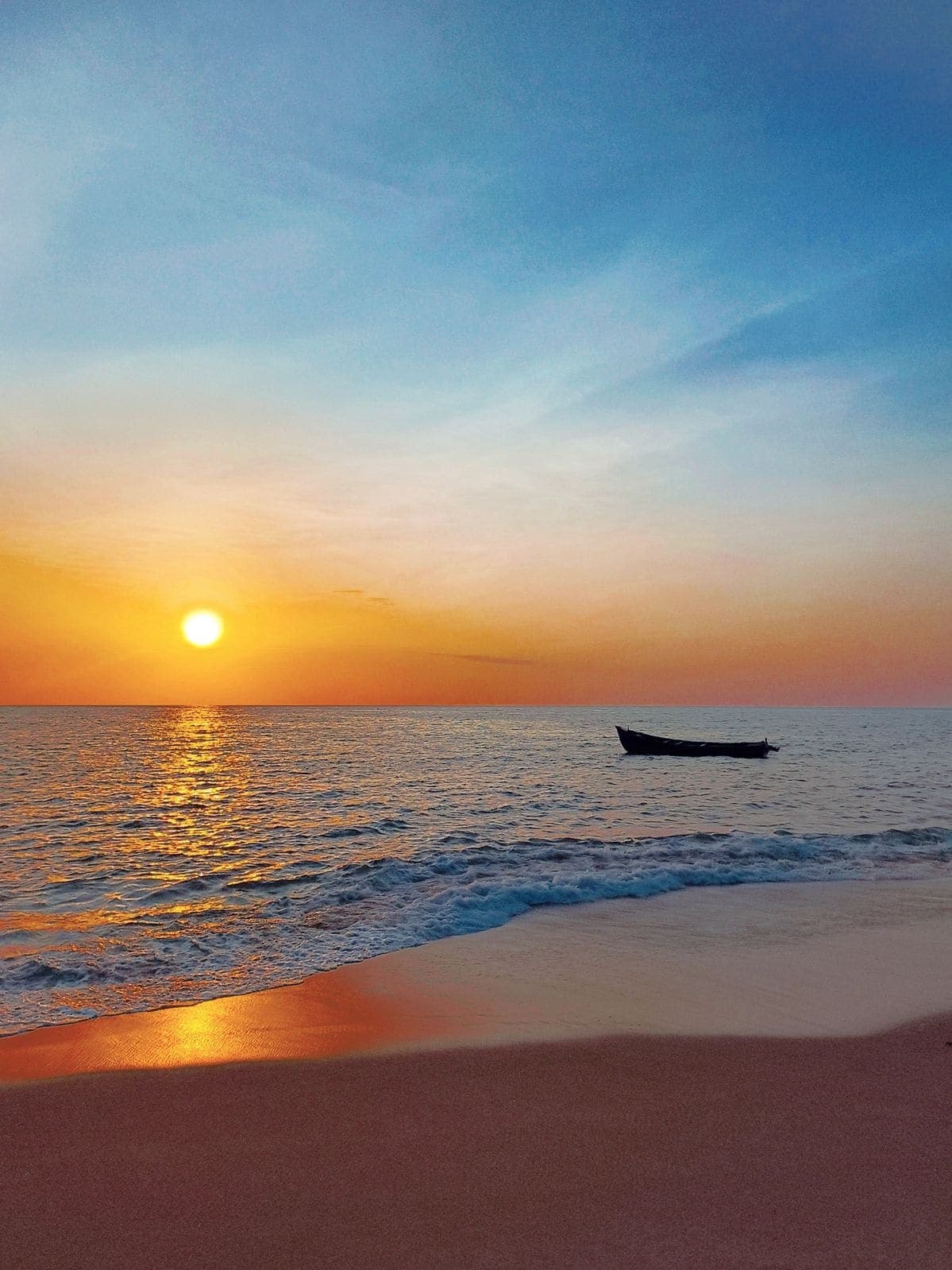 A fishing boat crossing the Arabian Sea at sunset off Thottam beach